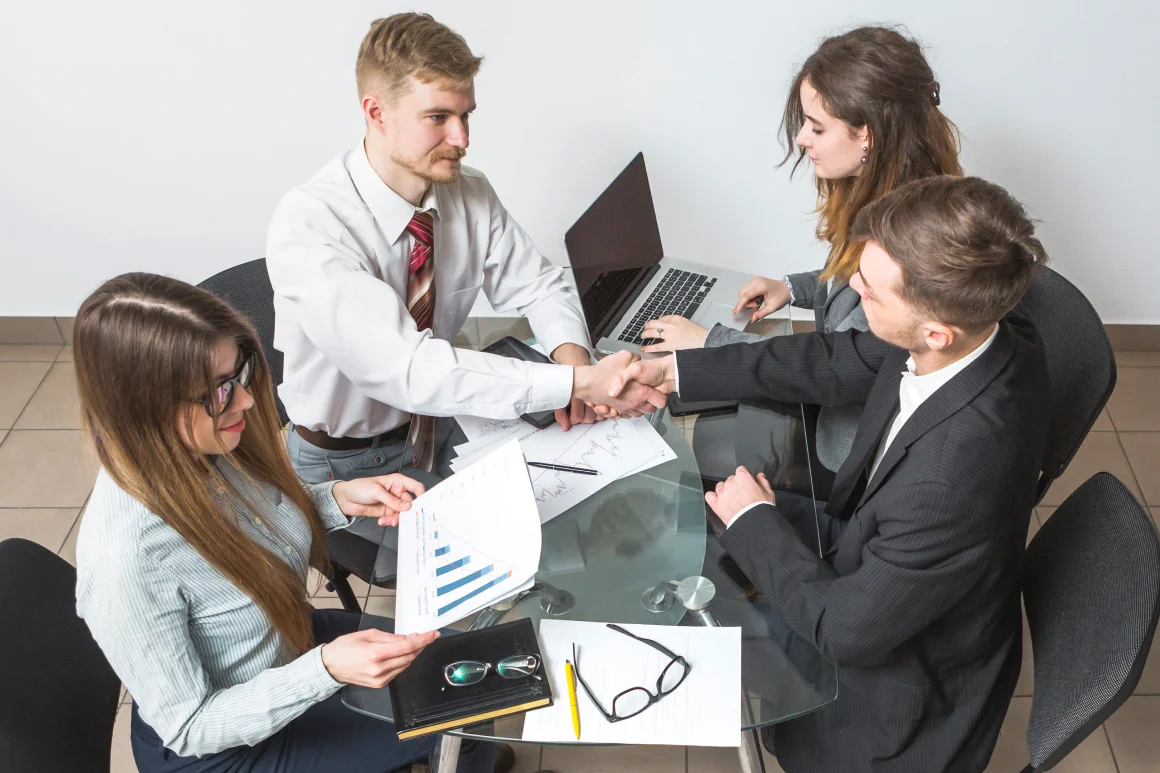 elevated-view-businessman-shaking-hands-with-his-partner-workplace